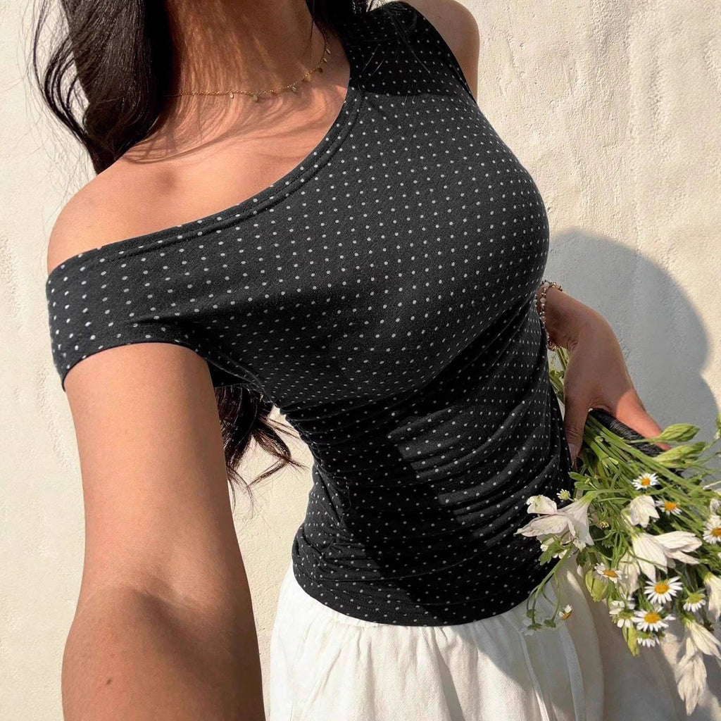 Woman wearing a black polka dot top holding flowers against a light background
