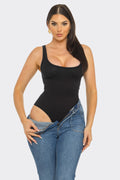 Woman wearing a black bodysuit and blue jeans on a white background