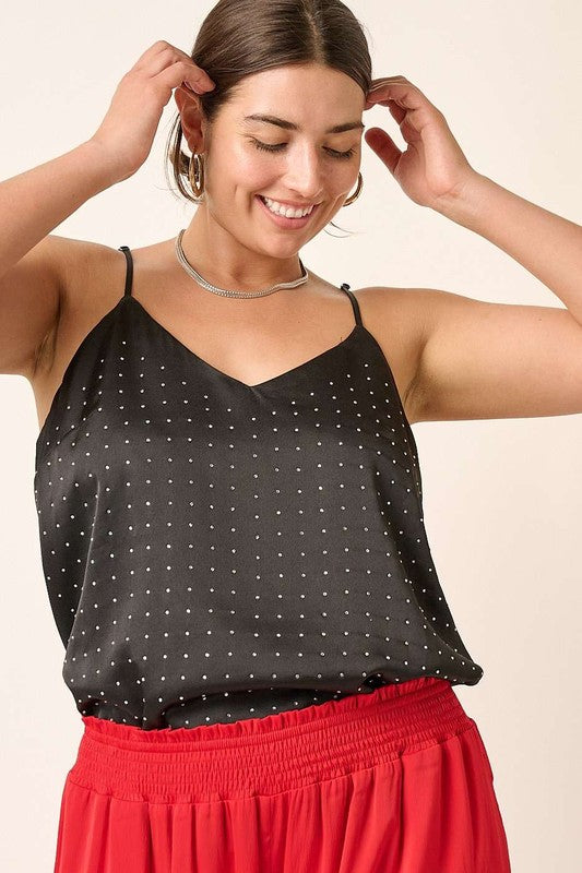 Woman wearing a black polka dot top and red pants against a beige background