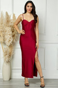 Woman in a red dress standing against a white paneled wall with decorative elements.