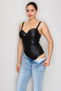 A woman modeling a black faux-leather corset-style camisole top with wide shoulder straps and gathered ruching, paired with light-wash blue jeans against a plain light gray studio background.
