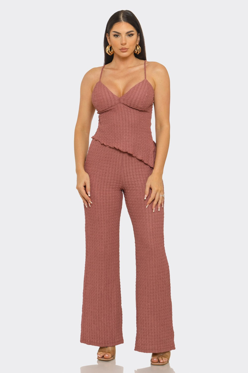 Woman wearing a pink ruffled jumpsuit on a white background